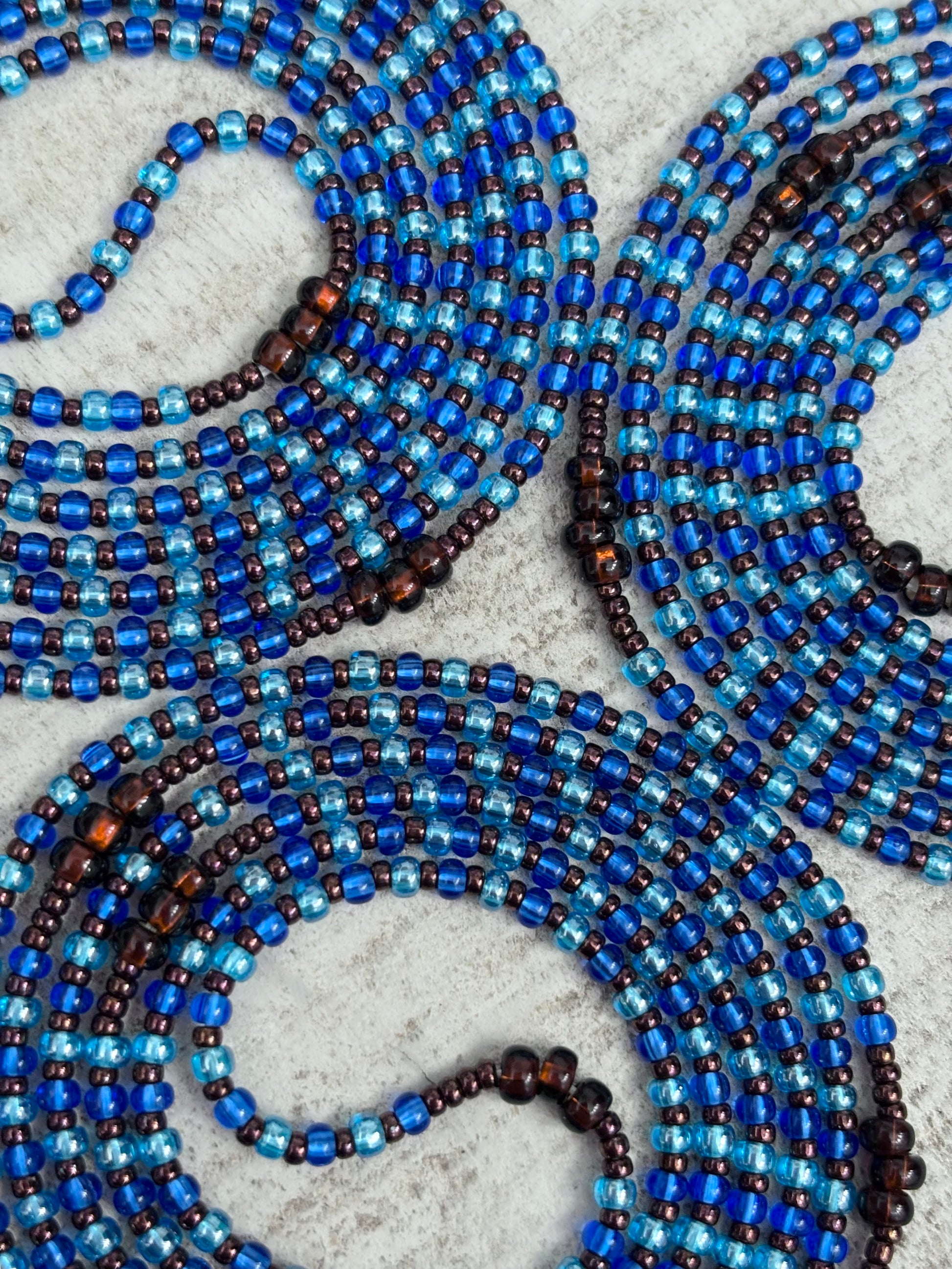 Blue and brown beaded waistbead on a textured surface