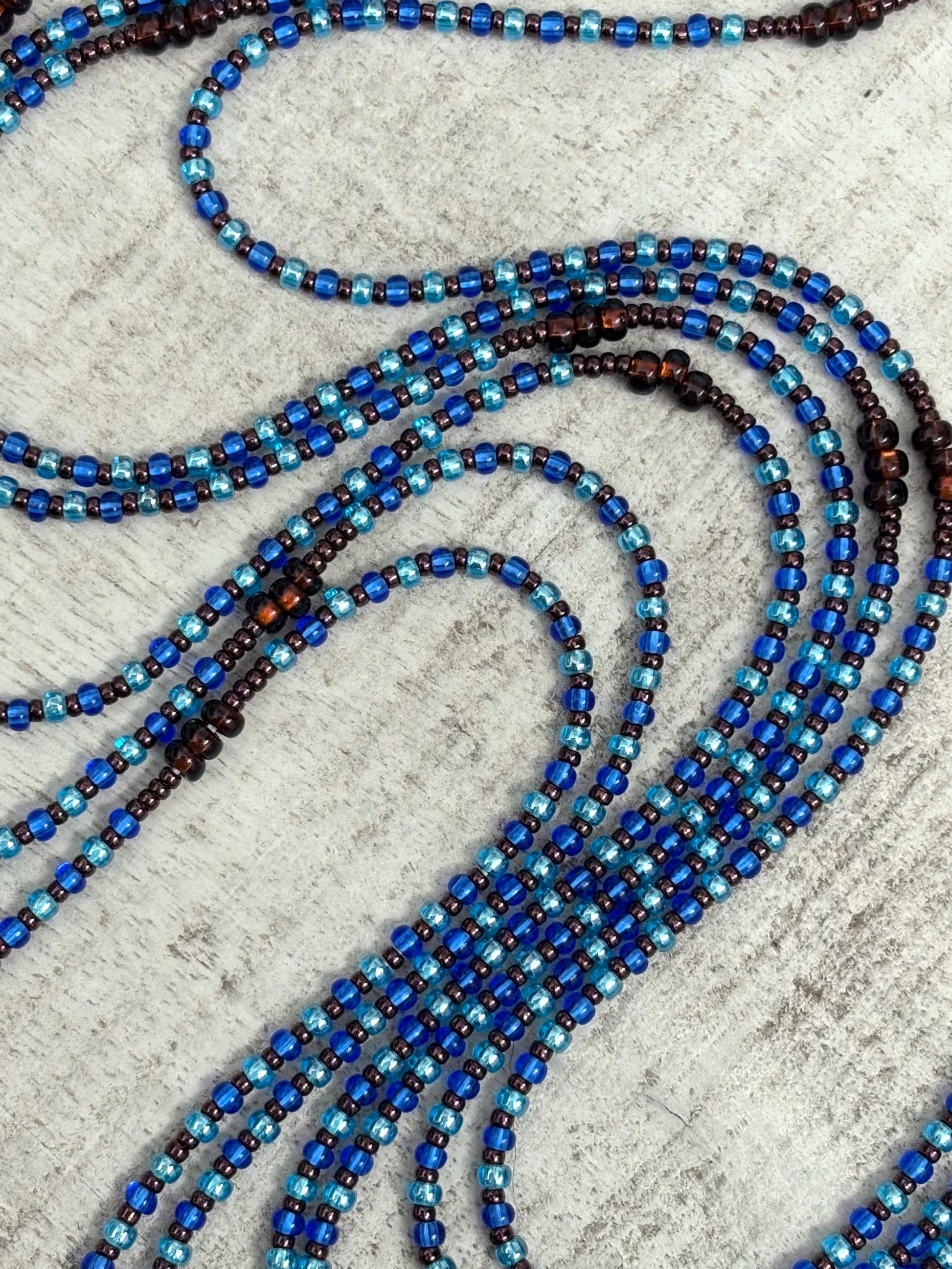 Blue and brown beaded waistbead on a textured surface