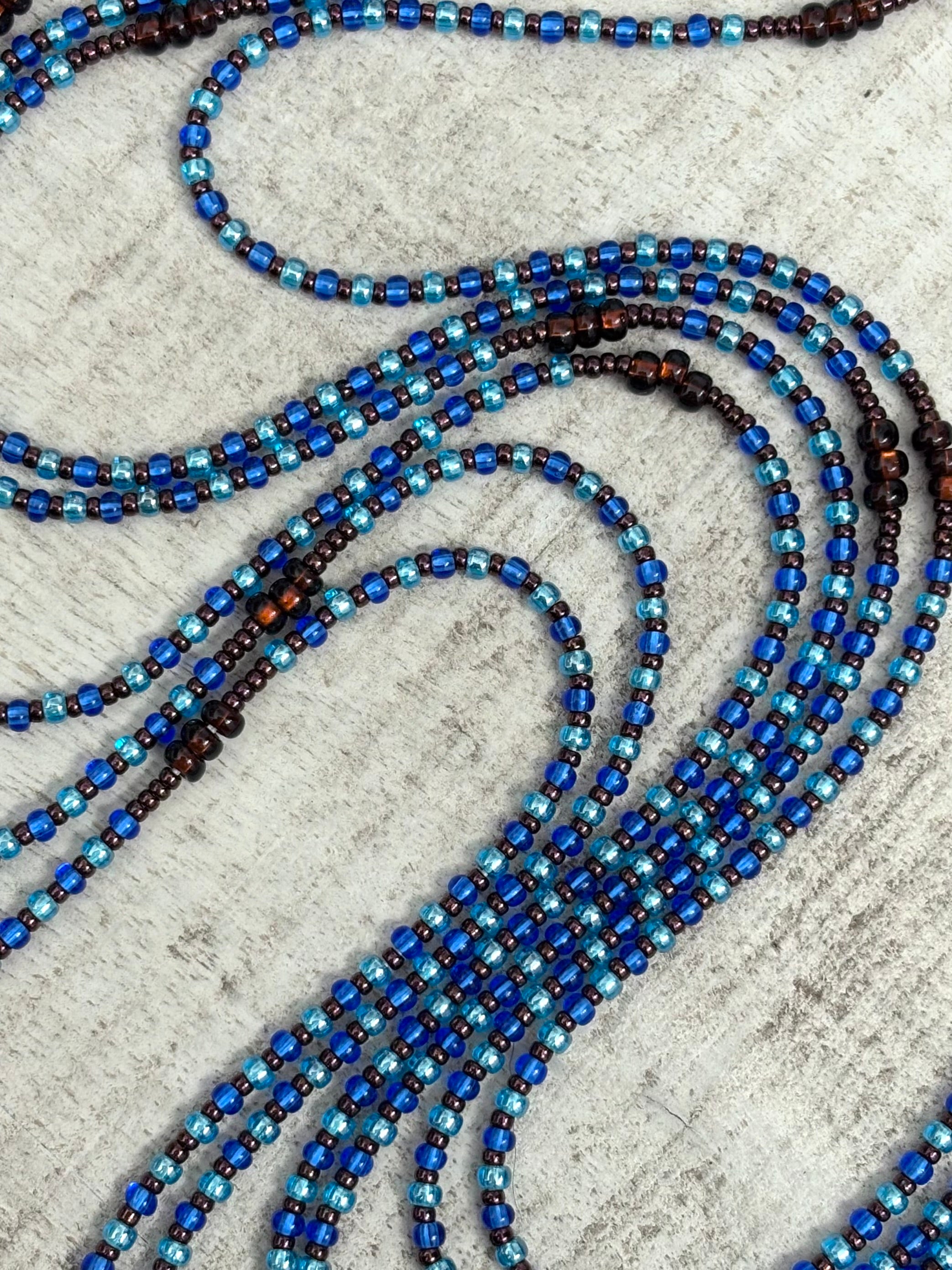Blue and brown beaded waistbead on a textured surface