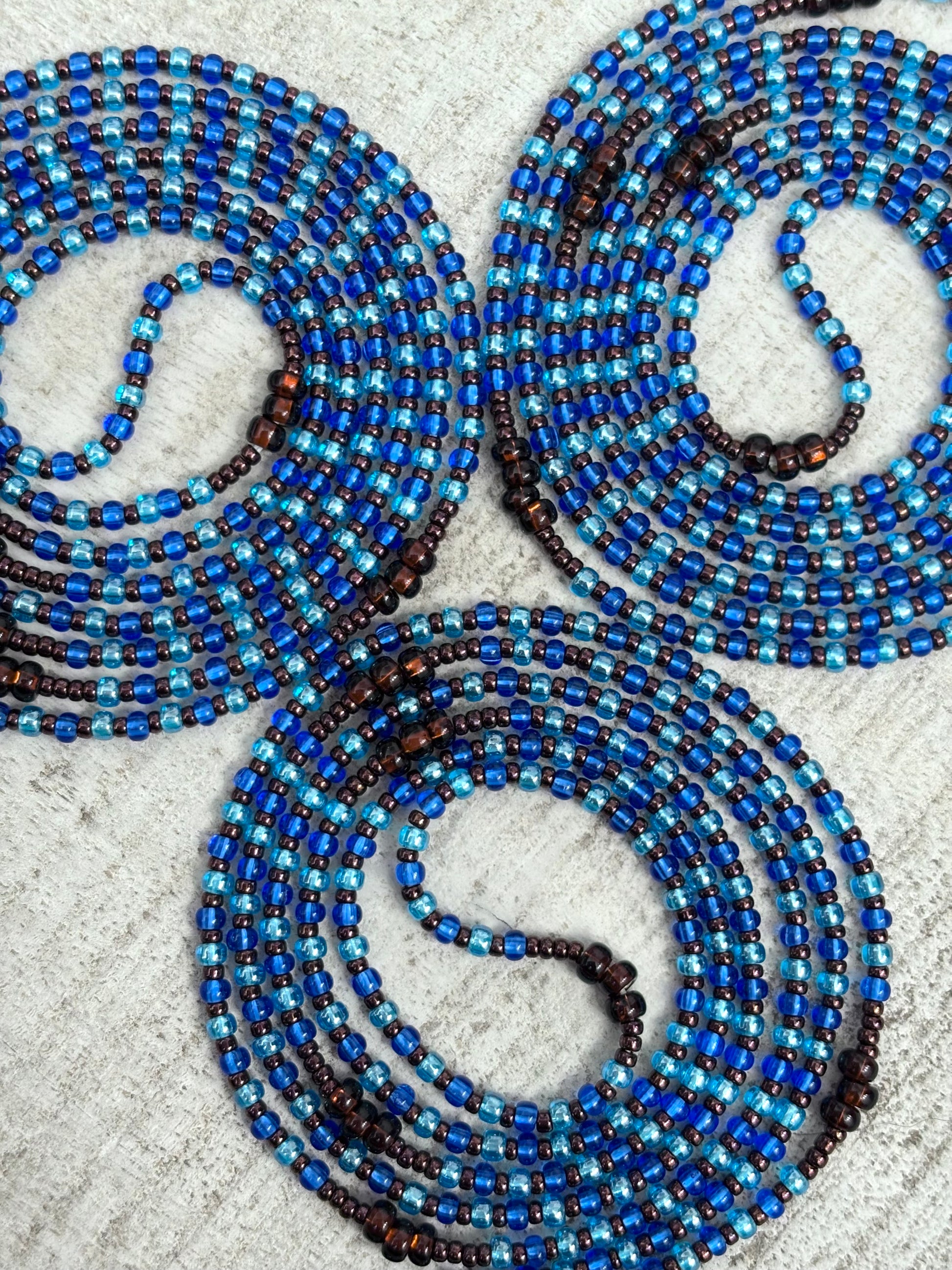 Blue and brown beaded waistbead on a textured surface
